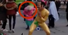 L’homme en costume doré danse au milieu de la rue. Mais regardez ce que fait la mamie avec le manteau rose!